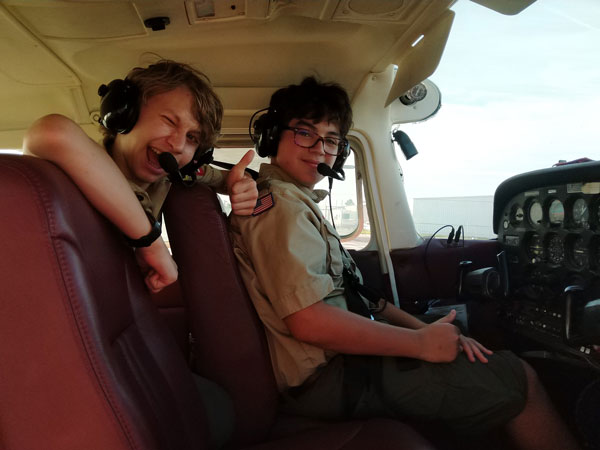 Two Scouts wearing aviation headsets inside a small airplane.